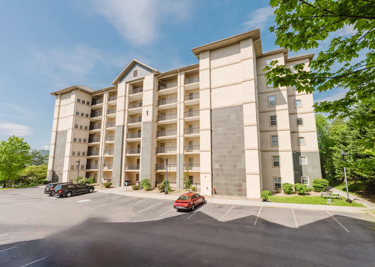 This exterior image highlights the building's inviting facade with balconies and lush greenery surrounding the property. The open, communal areas convey a sense of welcome and hint at the proximity to local attractions and group activities.