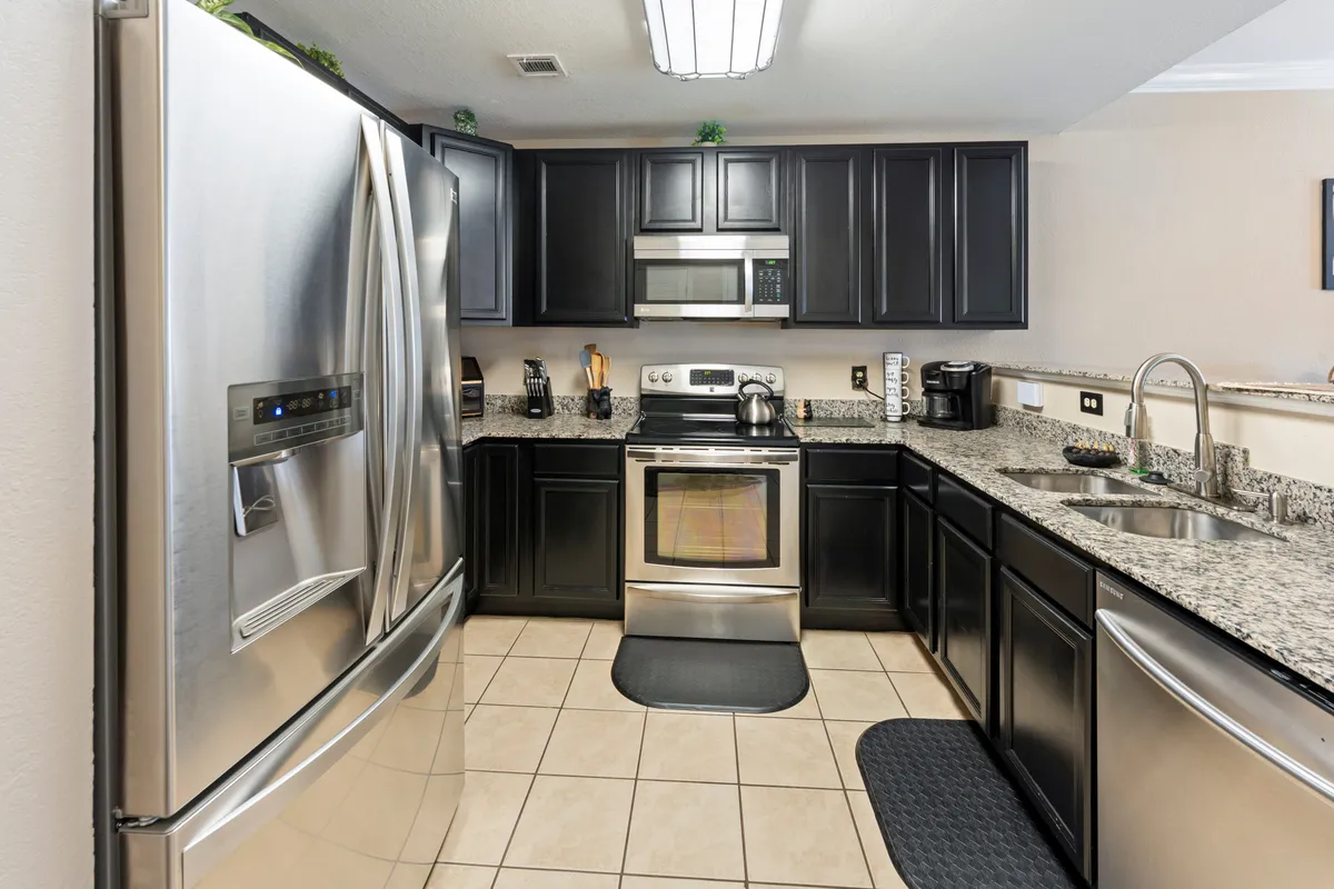 A modern kitchen featuring stainless steel appliances, granite countertops, and dark cabinetry. The space is brightly lit and arranged for both cooking and entertaining, with quality finishes and ample workspace.