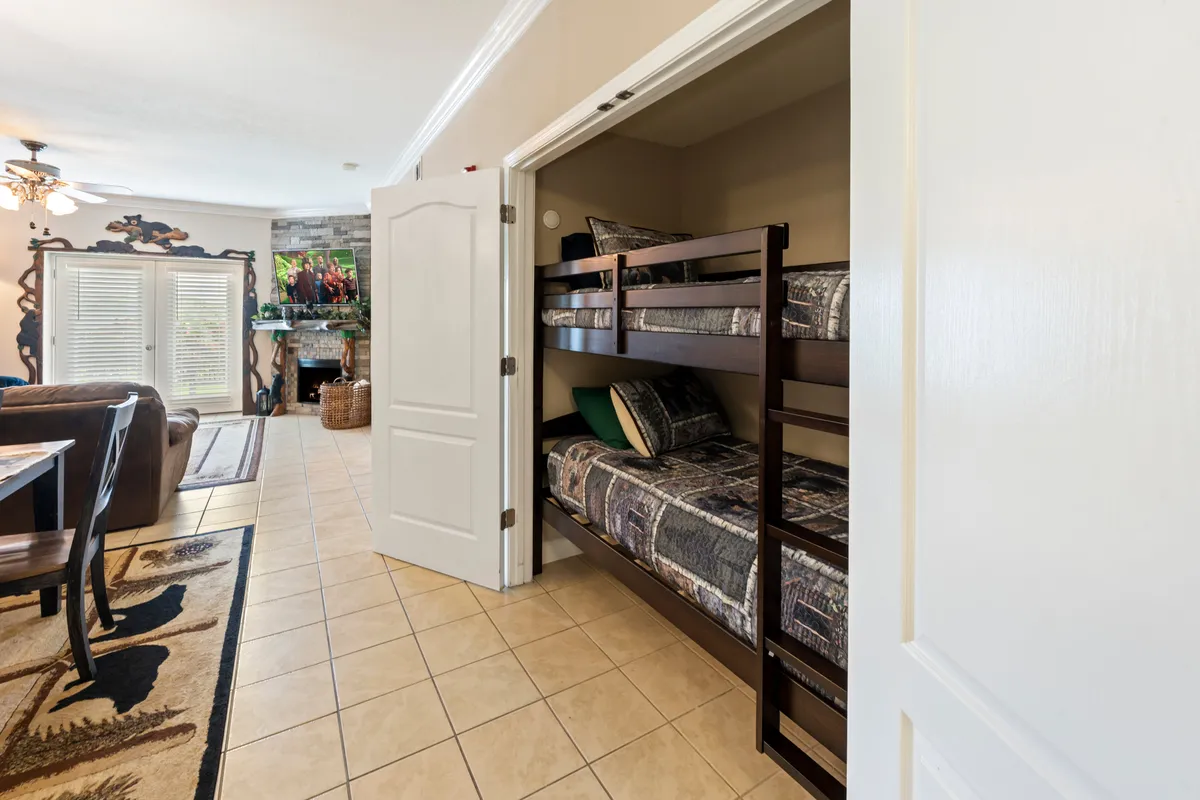 A multi-functional living space that includes bunk beds tucked to the side, a dining table for gatherings, and a cozy living area with a fireplace. The arrangement suggests flexibility for sleeping, dining, and relaxing—all in one communal area.